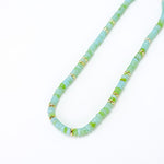 Necklace with light blue and green beads and gold accents on a white background