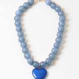 Necklace with blue beads and a blue heart-shaped pendant on a white background