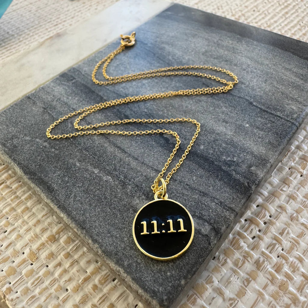 Picture of a fine gold chain necklace with a black disc 11:11 pendant.