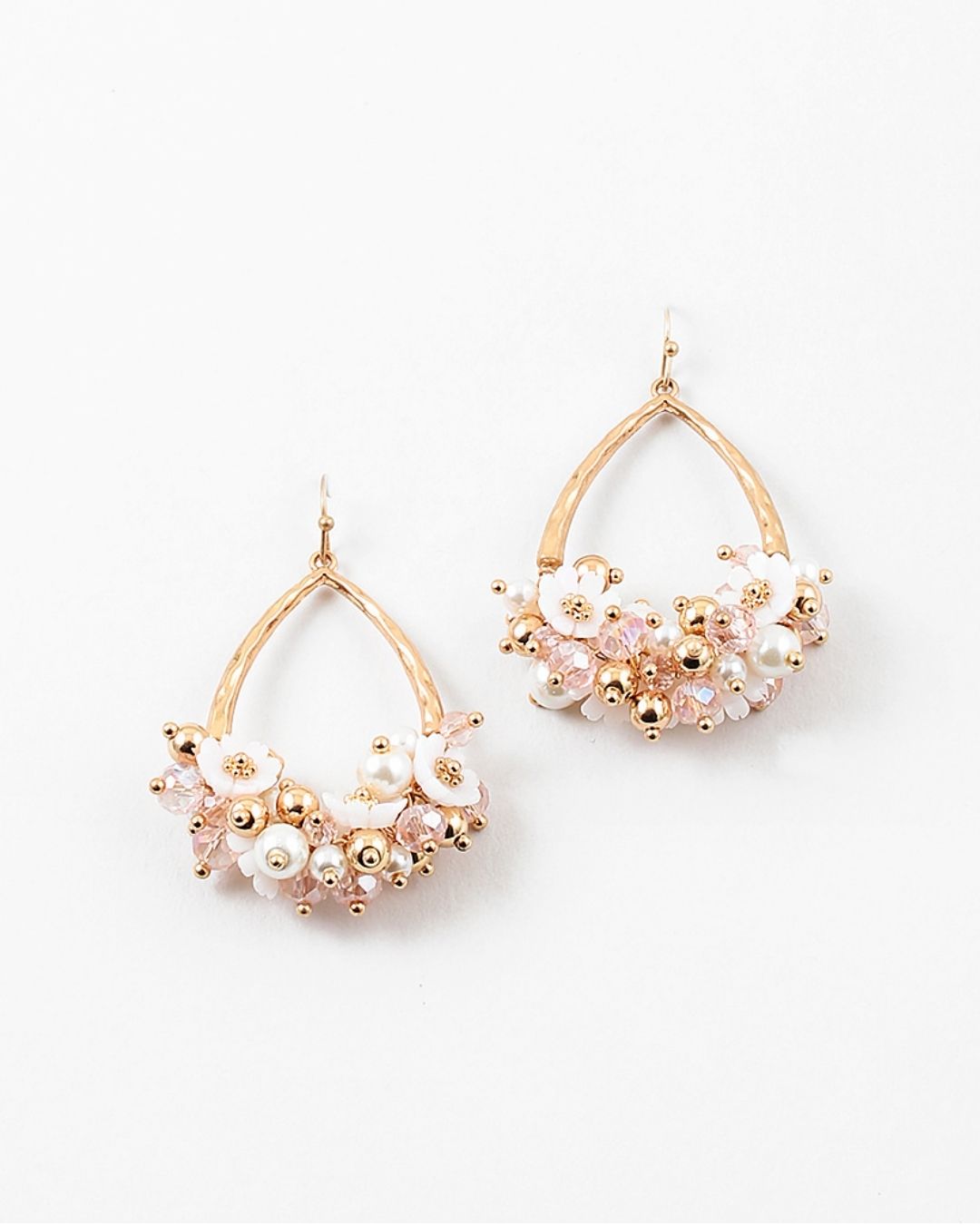 Gold and pearl dangle earrings with floral decor on a white background