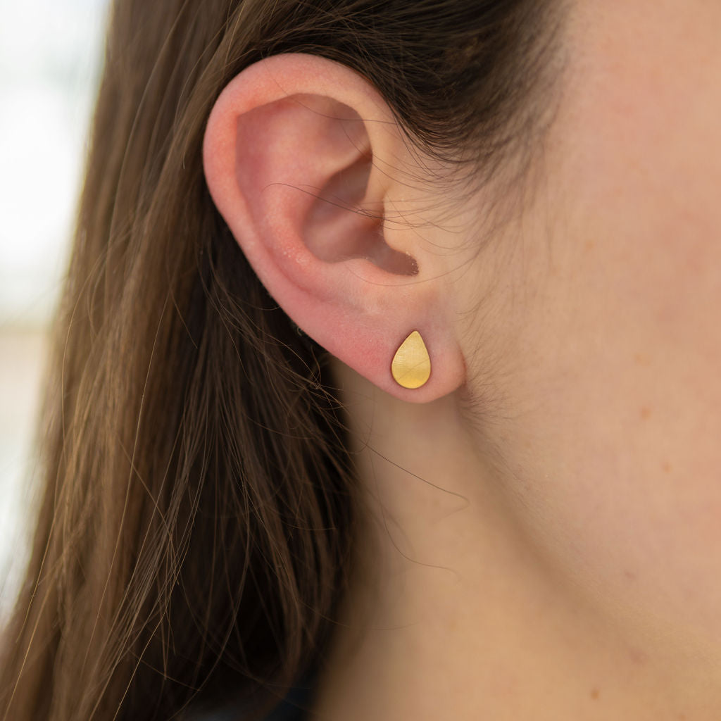 Woman wearing gold teardrop stud earrings