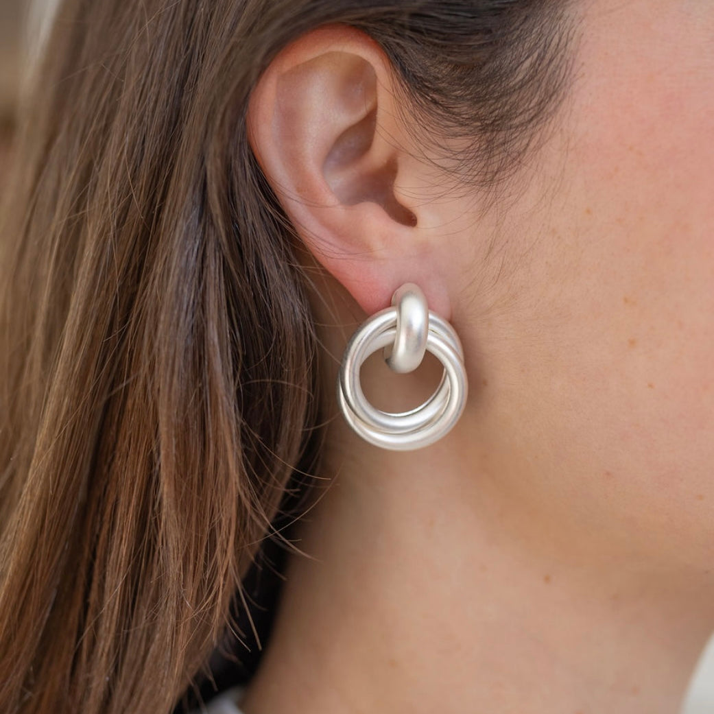 Picture of model wearing white silver looped earrings.