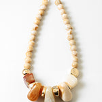 Necklace with beige beads and large decorative stone and gold elements on a white background