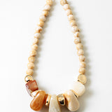 Necklace with beige beads and large decorative stone and gold elements on a white background