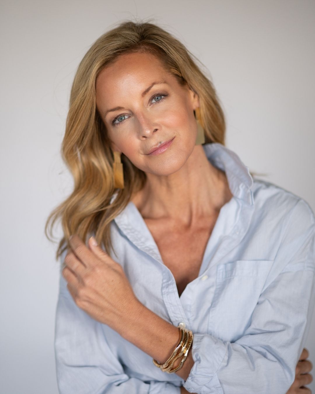 Woman wearing a light blue button up shirt against a plain background