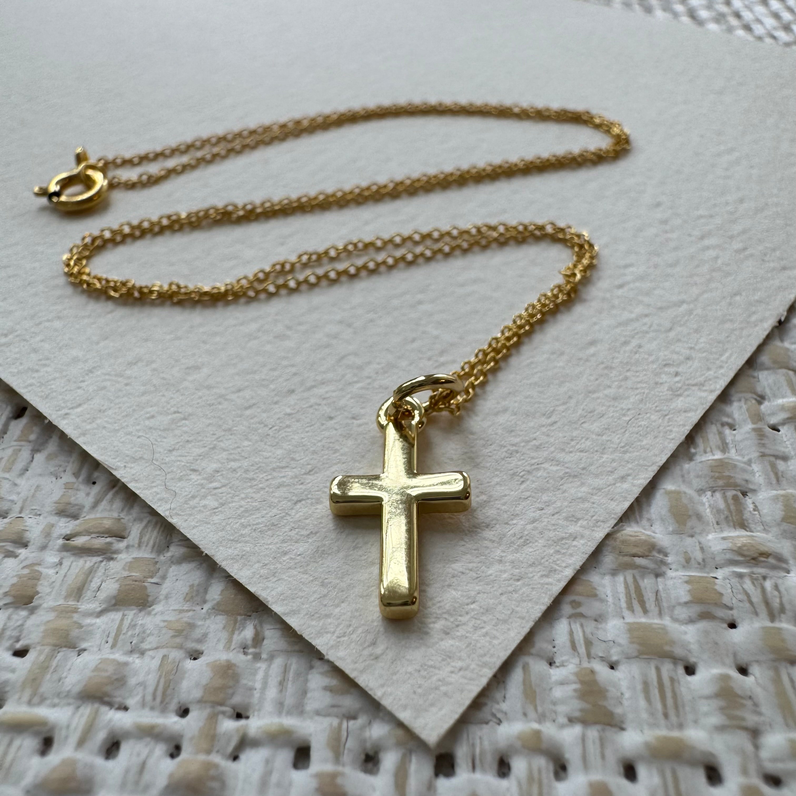 Gold cross necklace on a textured surface