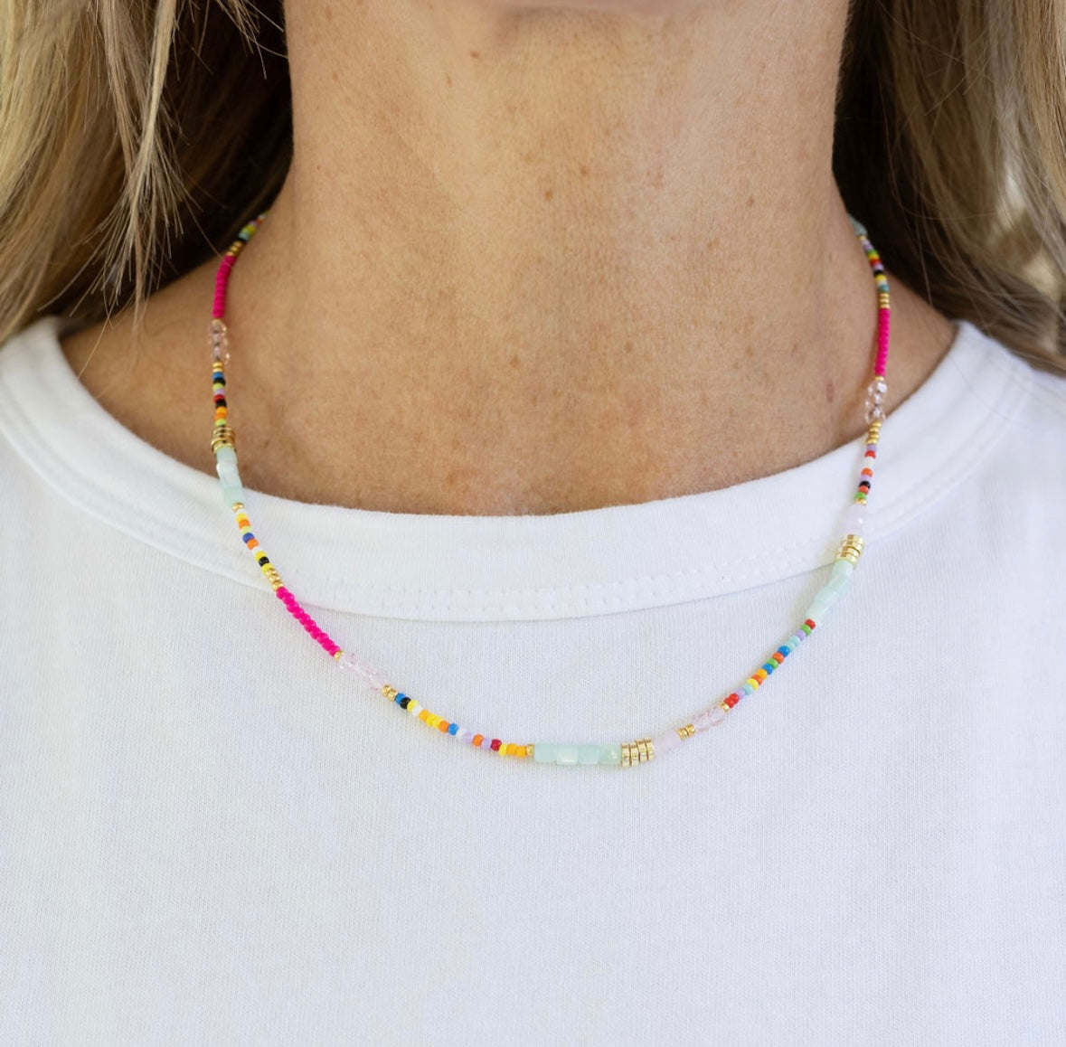 Colorful tiny beaded necklace worn by a person on a white background