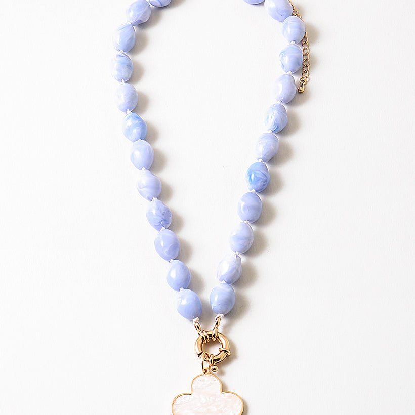 Necklace with blue beads and a gold clover-shaped pendant on a white background