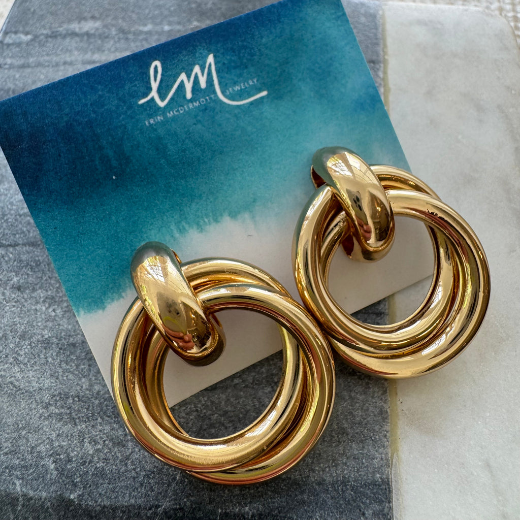Picture of a set of unique hoop earrings. Earrings have one small chunky hoop as the base with two gold hoops looped through it.