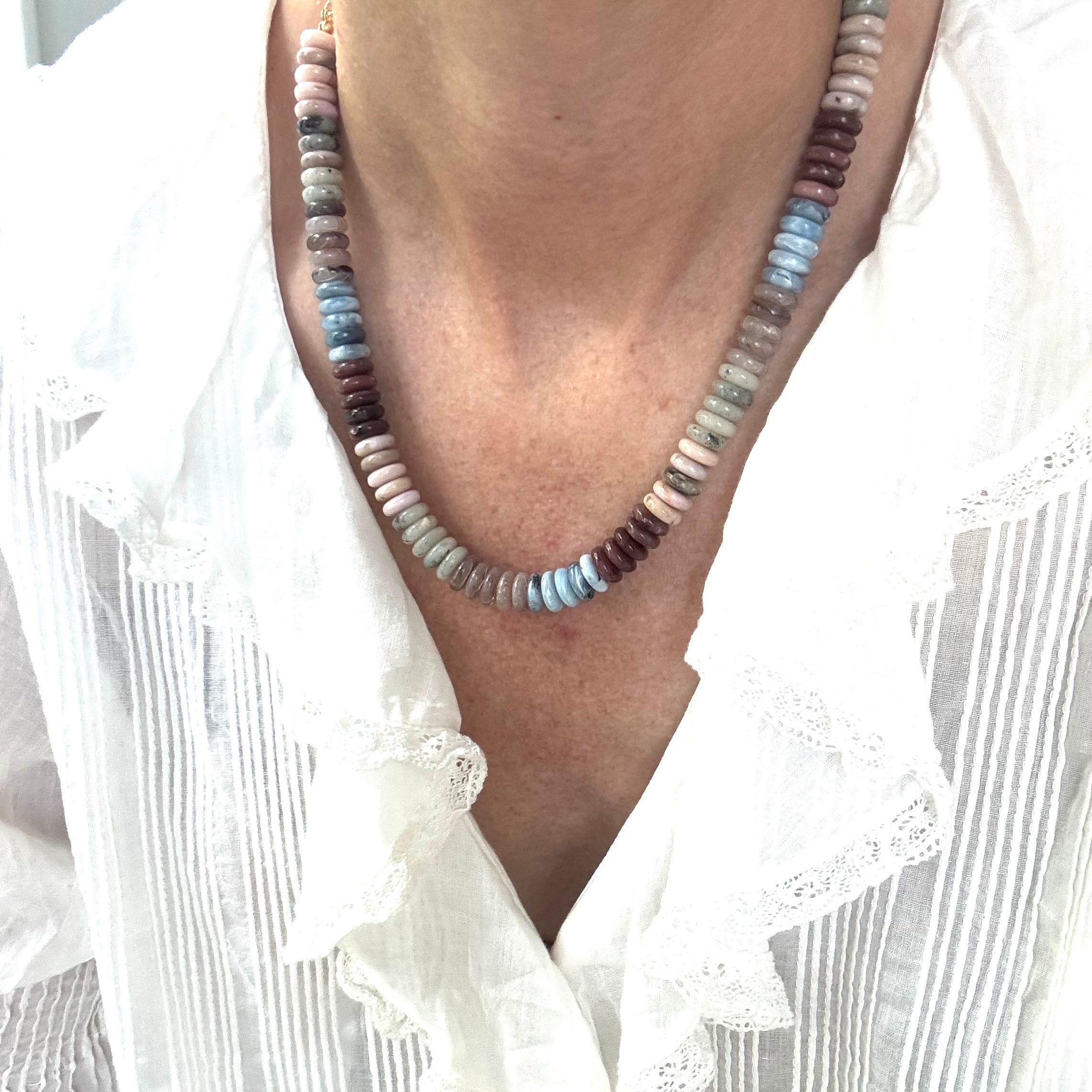 Necklace with multicolored beads worn by a person in a white shirt.
