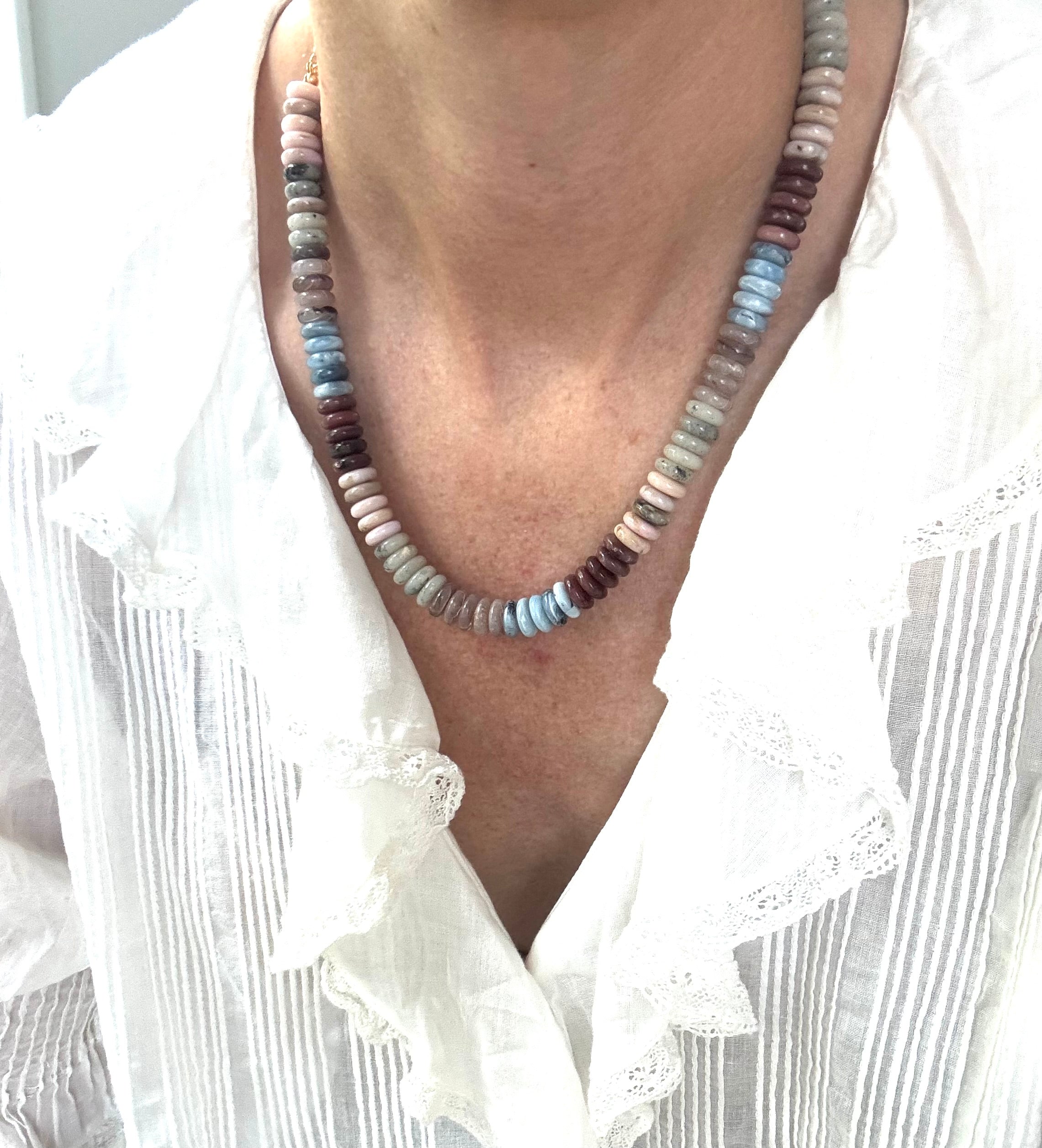 Necklace with multicolored beads worn by a person in a white shirt.