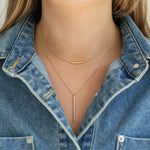 Gold bar necklaces on a person wearing a denim jacket