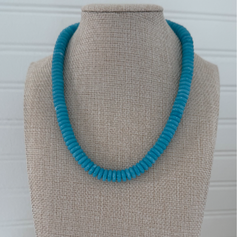 Turquoise necklace on a beige mannequin bust against a white background