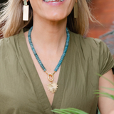 Picture of model wearing a a turquoise beaded necklace with a chunky gold link and large gold heart shaped pendant with a diamond at it's center.