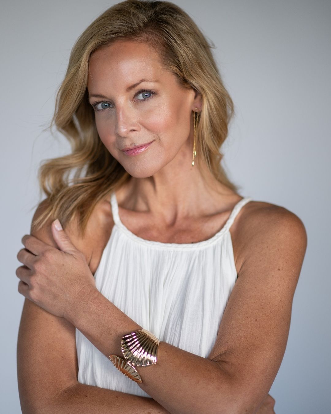 Woman wearing a white sleeveless top with a plain background