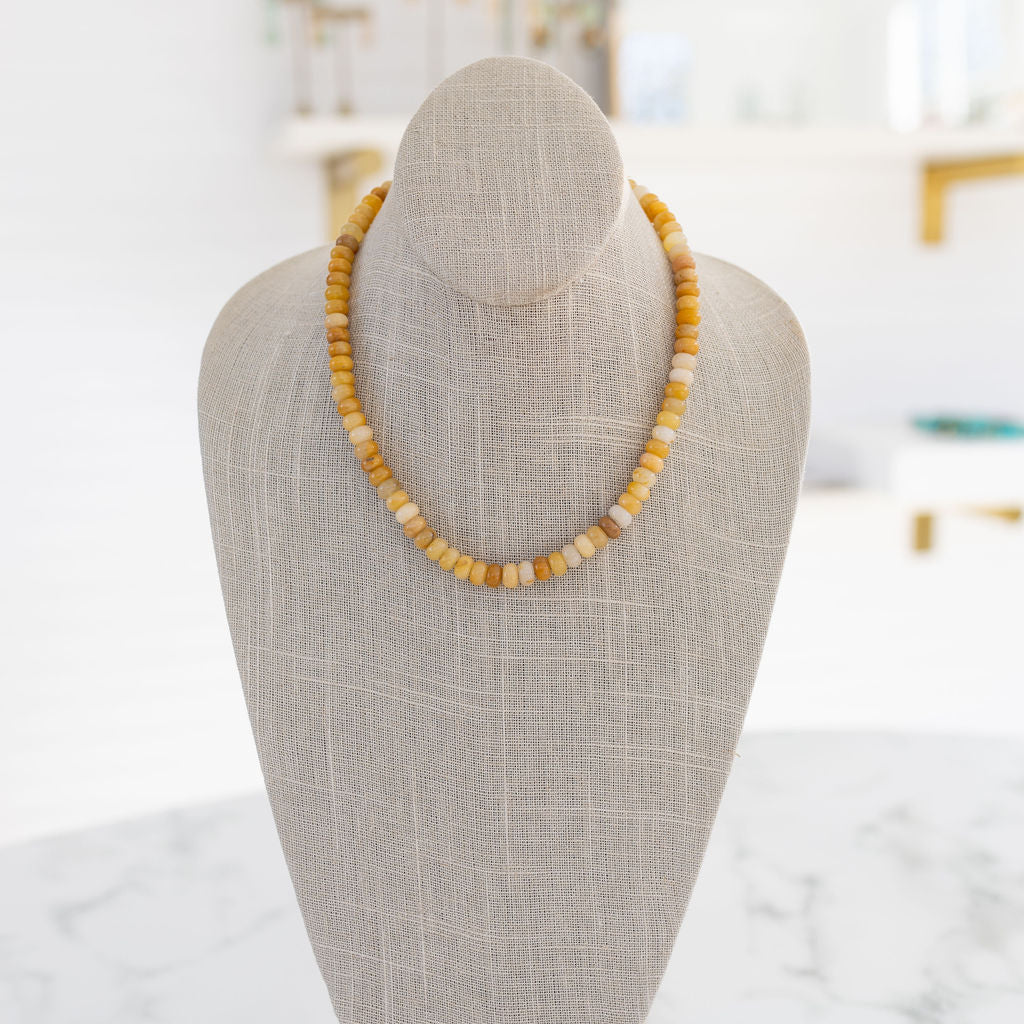 A gemstone necklace displayed on a mannequin torso with a predominantly yellow beads, arranged in a single strand.