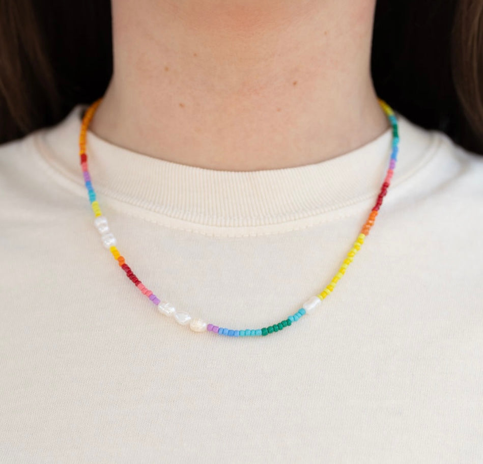 Picture of model wearing a multicolored necklace made of small beads and freshwater pearls.