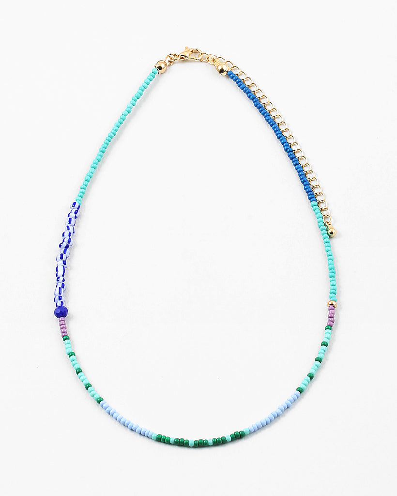 Dainty bead necklace in light blue, green and teal beads with some larger dark blue and striped beads.