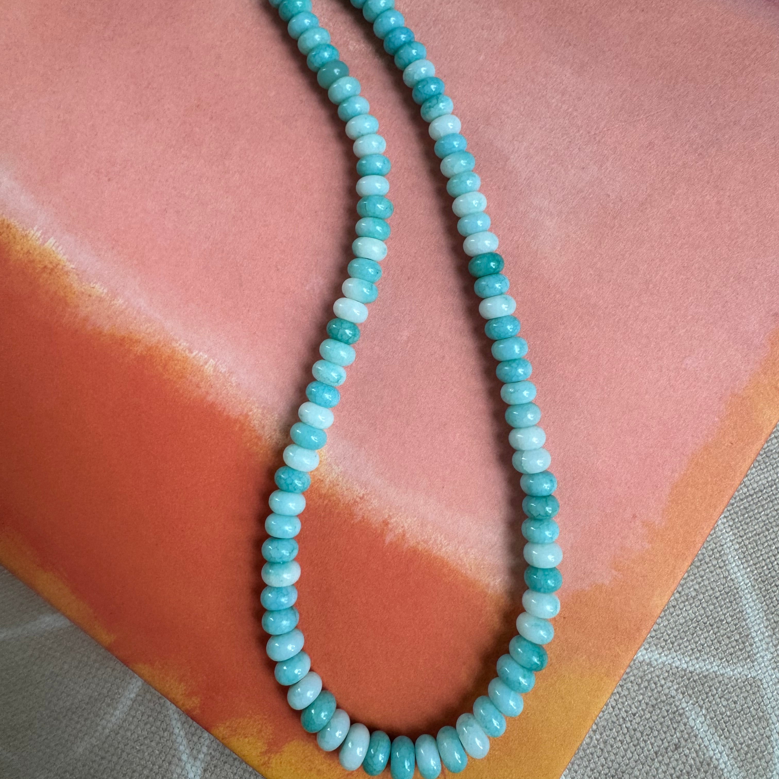 Turquoise beaded necklace on a pink surface