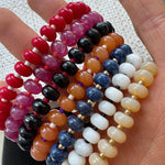 Colorful beaded bracelets on a hand with a textured background