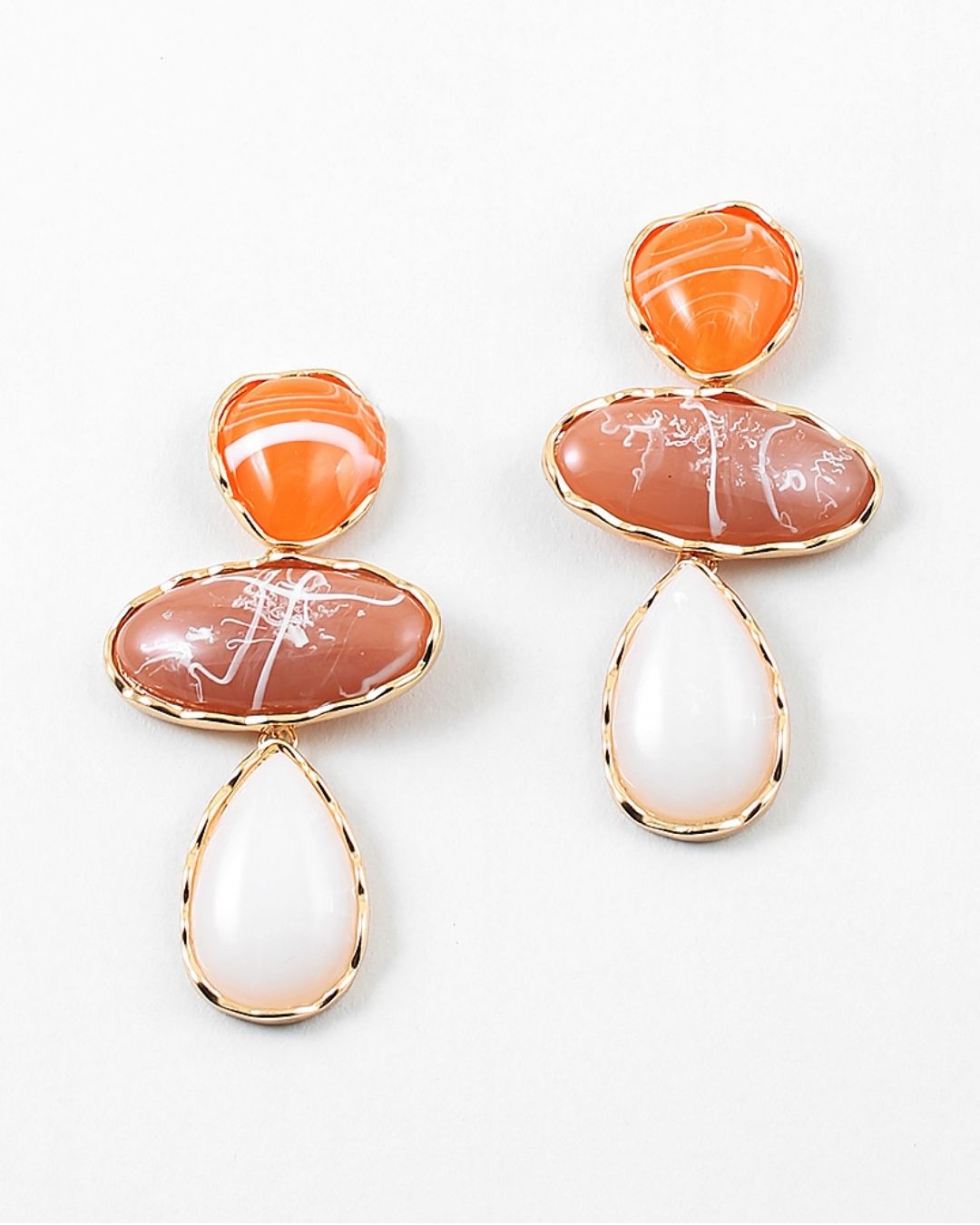 Pair of large dangle earrings with orange, pink, and white stone drops on a white background