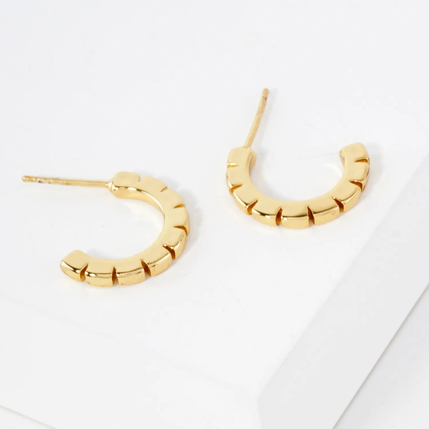 Gold hoop earrings on a light gray background