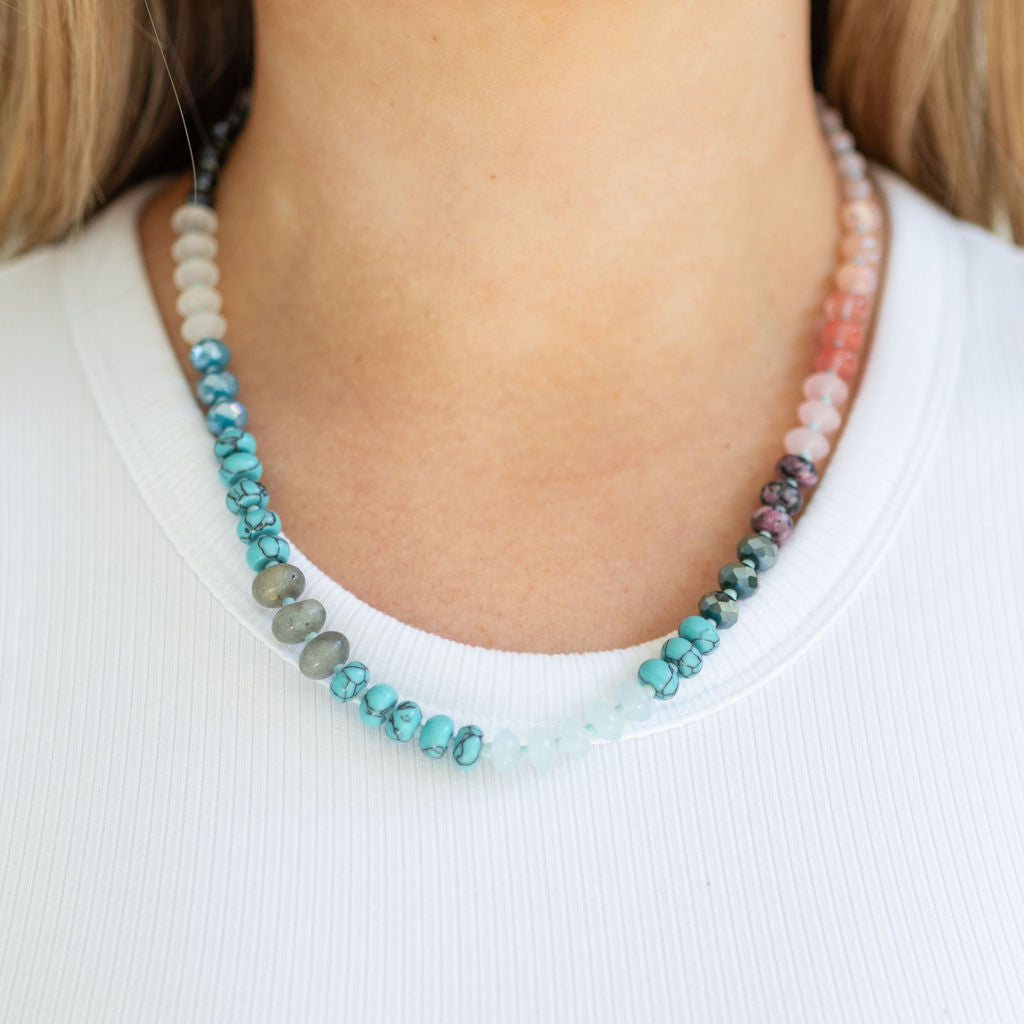 Necklace with multicolored beads worn by a person on a white background