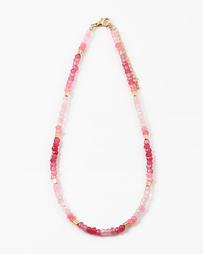 Necklace with pink beads and gold accents on a white background