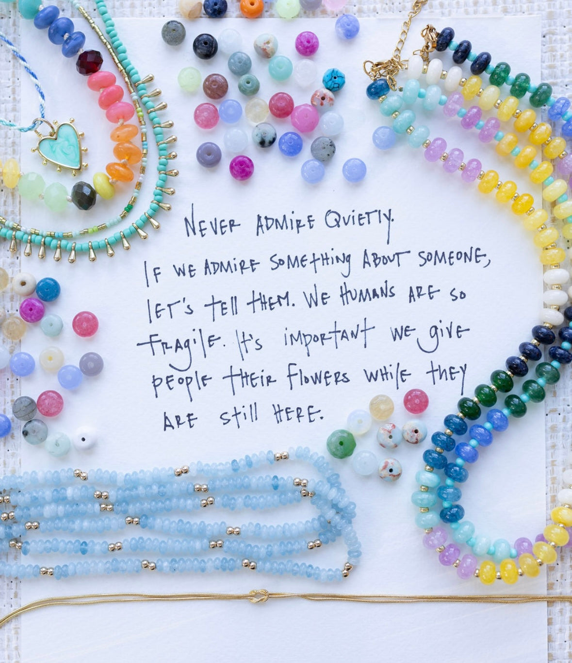 Advertisement showing many colorful beads and various necklaces with the text,"Never admire quietly. If we admire something about someone, let's tell them. We humans are so fragile. It's important we give people their flowers while they are still here."