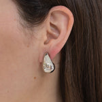 Picture of model wearing a chunky silver teardrop earring.