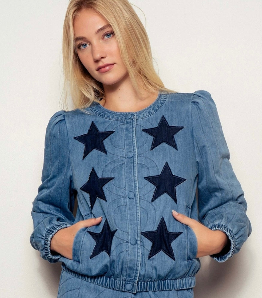 Woman wearing a denim jacket with star patterns on a plain background