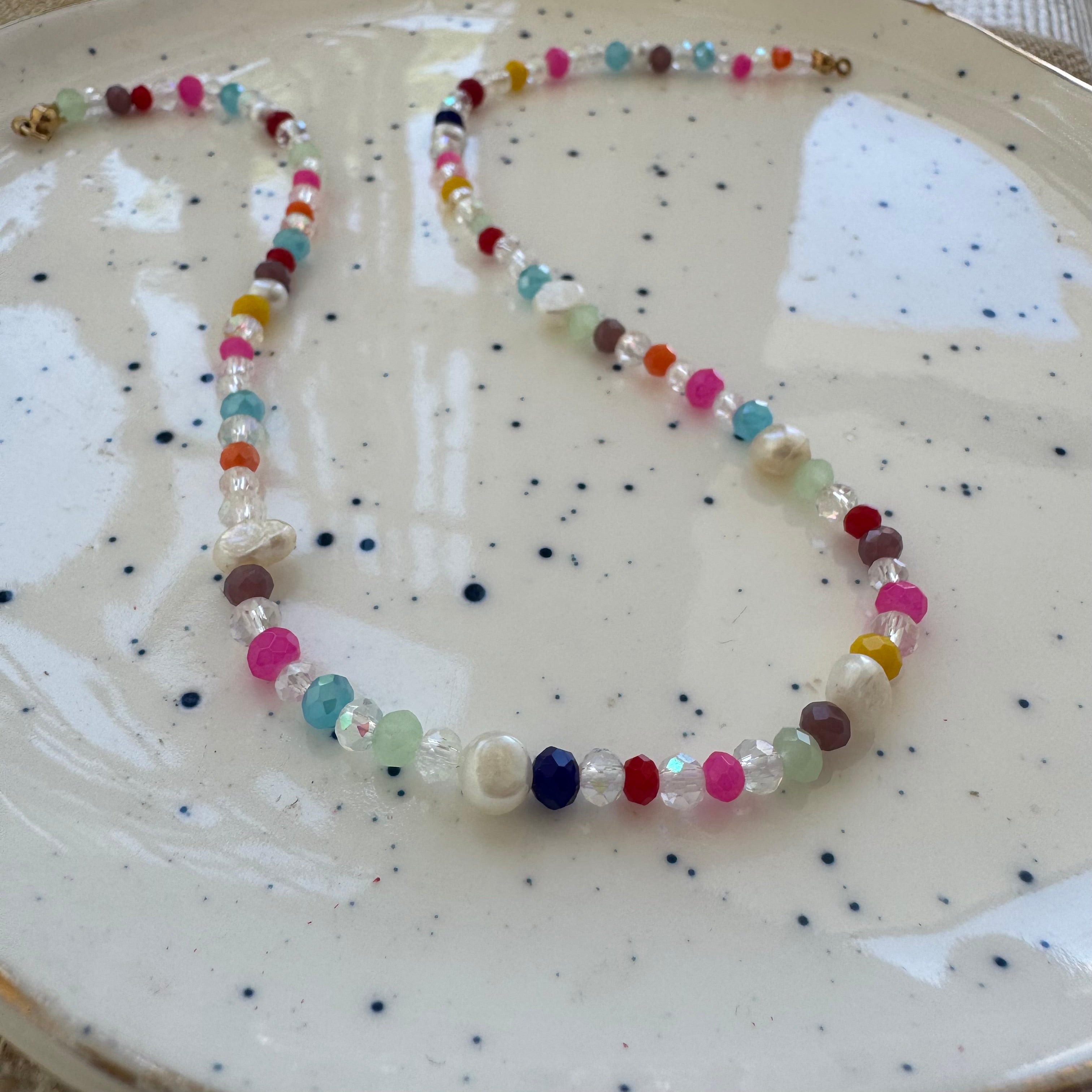 Colorful and clear beaded necklace on a speckled ceramic plate