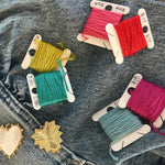 Picture of varying shades of thread and two heart pendants against a denim background