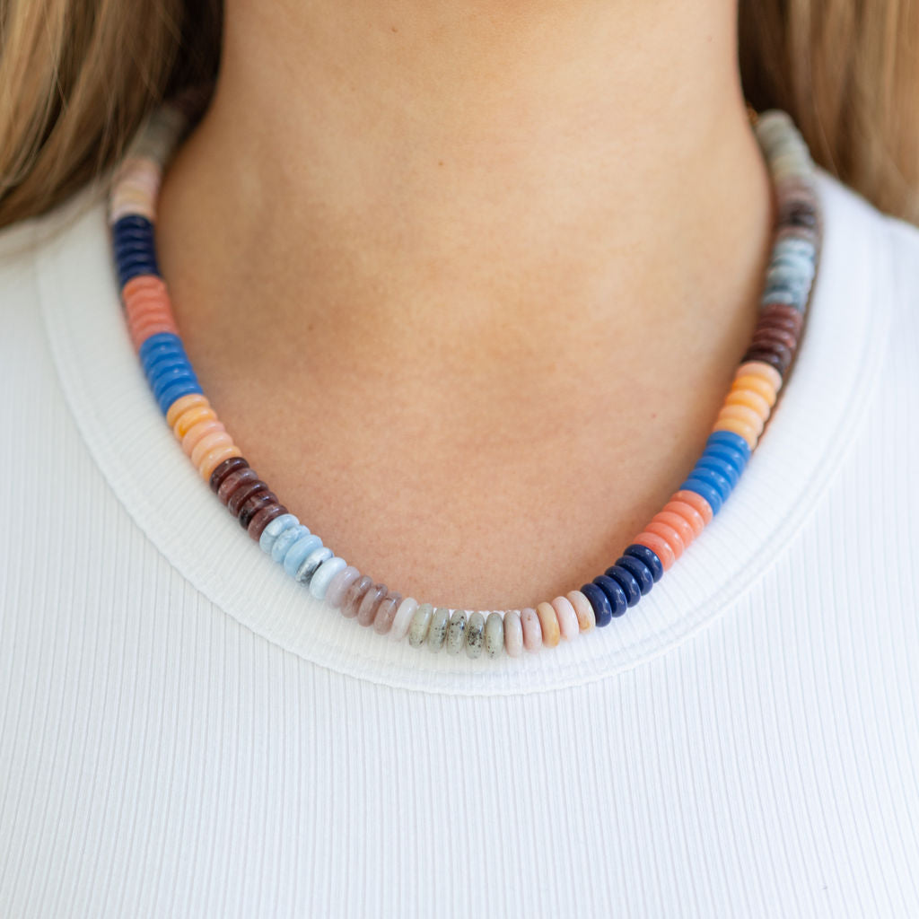 Colorful beaded necklace worn by a person on a plain background