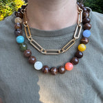 Necklace with multicolored beads and gold chain on a person wearing a green shirt.