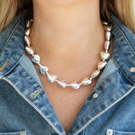 Silver heart bead necklace worn by a person with a denim jacket