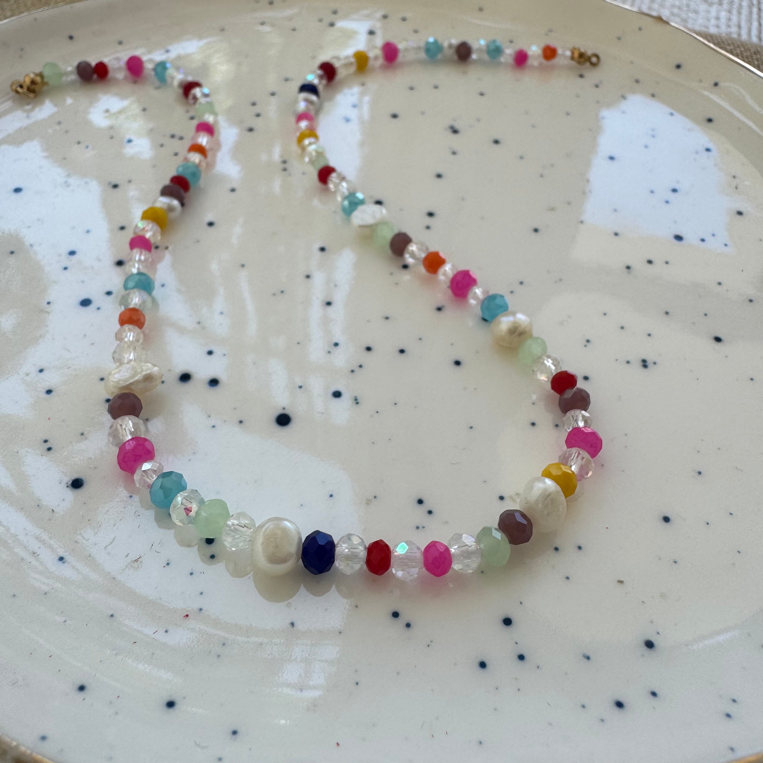 Colorful and clear beaded necklace on a speckled ceramic plate