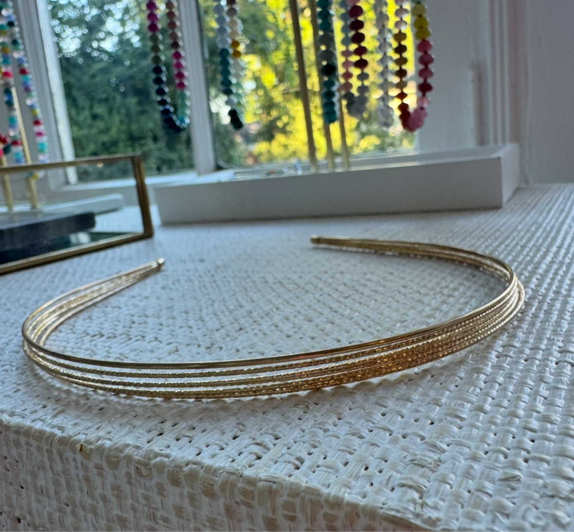 Gold headband on a textured surface with colorful beads in the background