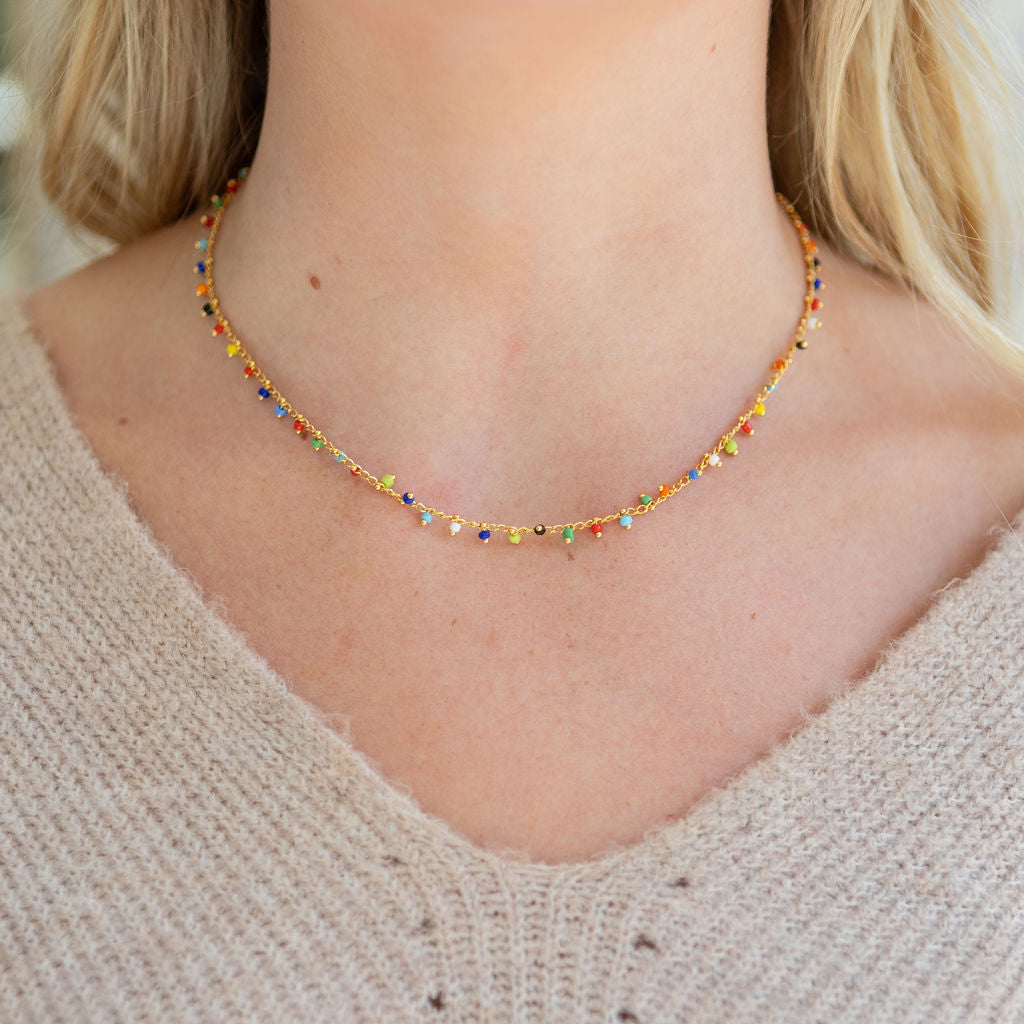 Delicate colorful beaded necklace worn by a person with a neutral background