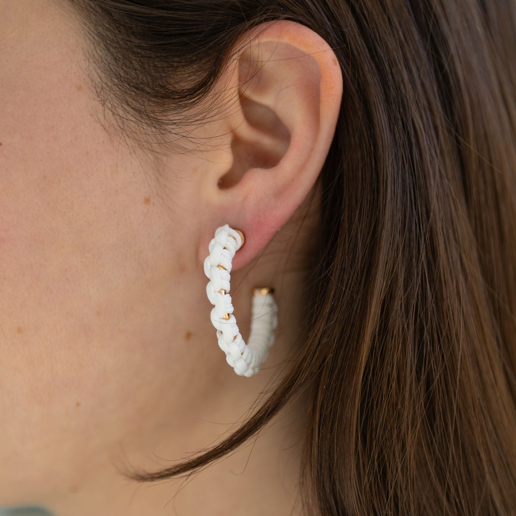 A close-up image of a person wearing faux leather wrapped cream hoop earrings.