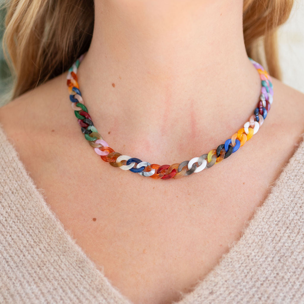Multicolored chain necklace on a person wearing a beige sweater.
