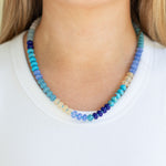 Necklace with blue and green beads worn by a person on a white background