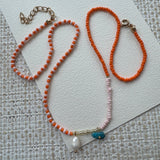Dainty bead necklace with red and white beads and a small fresh water pearl and turquoise stone pendants.