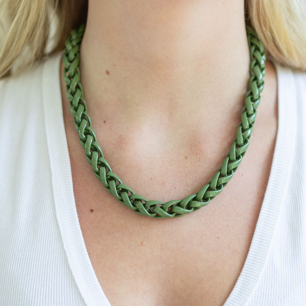 Woven green plastic rope necklace on a person wearing a white top