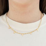Gold necklace with gold tabs worn by a person on a white background