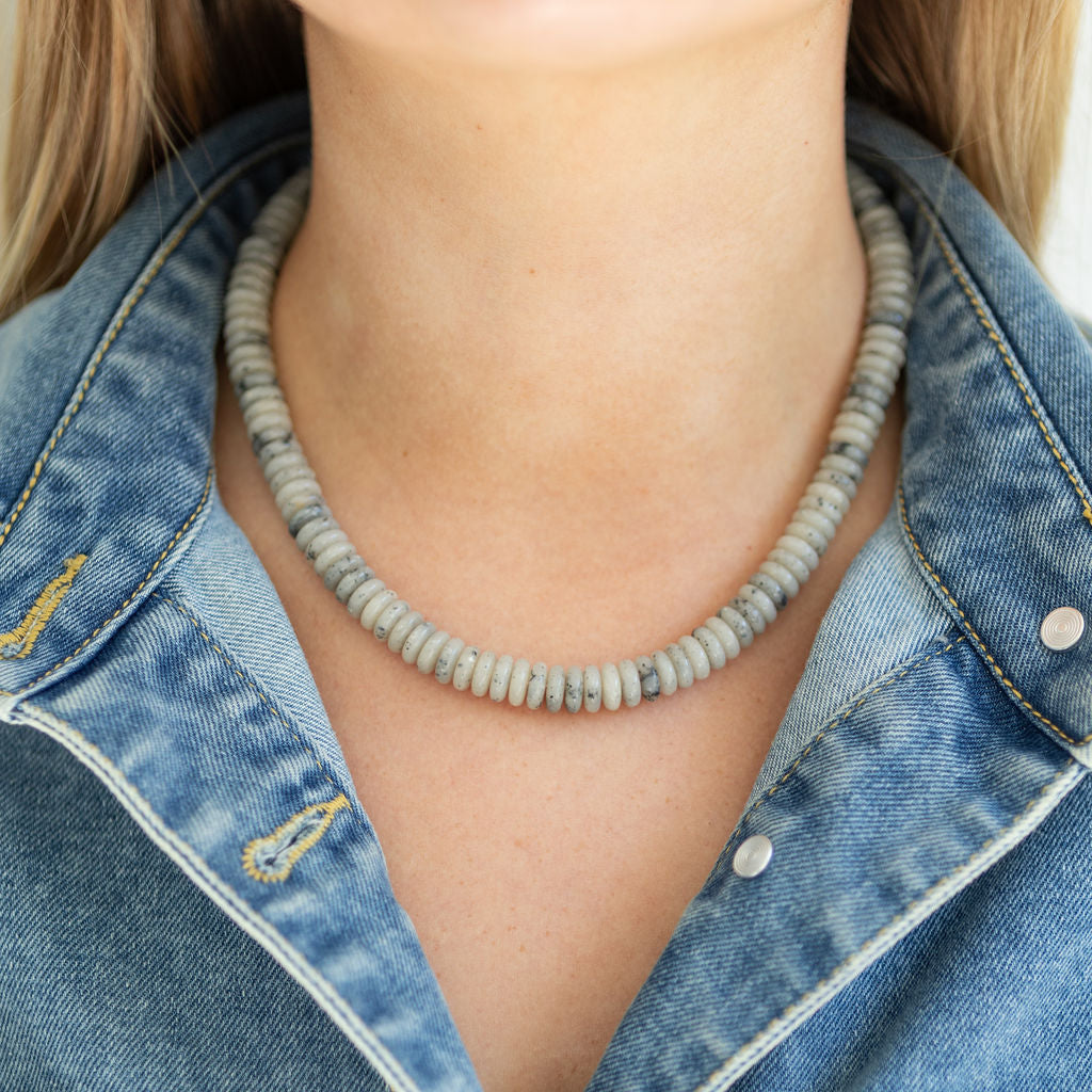 Gray stone bead necklace worn by a person with a denim jacket
