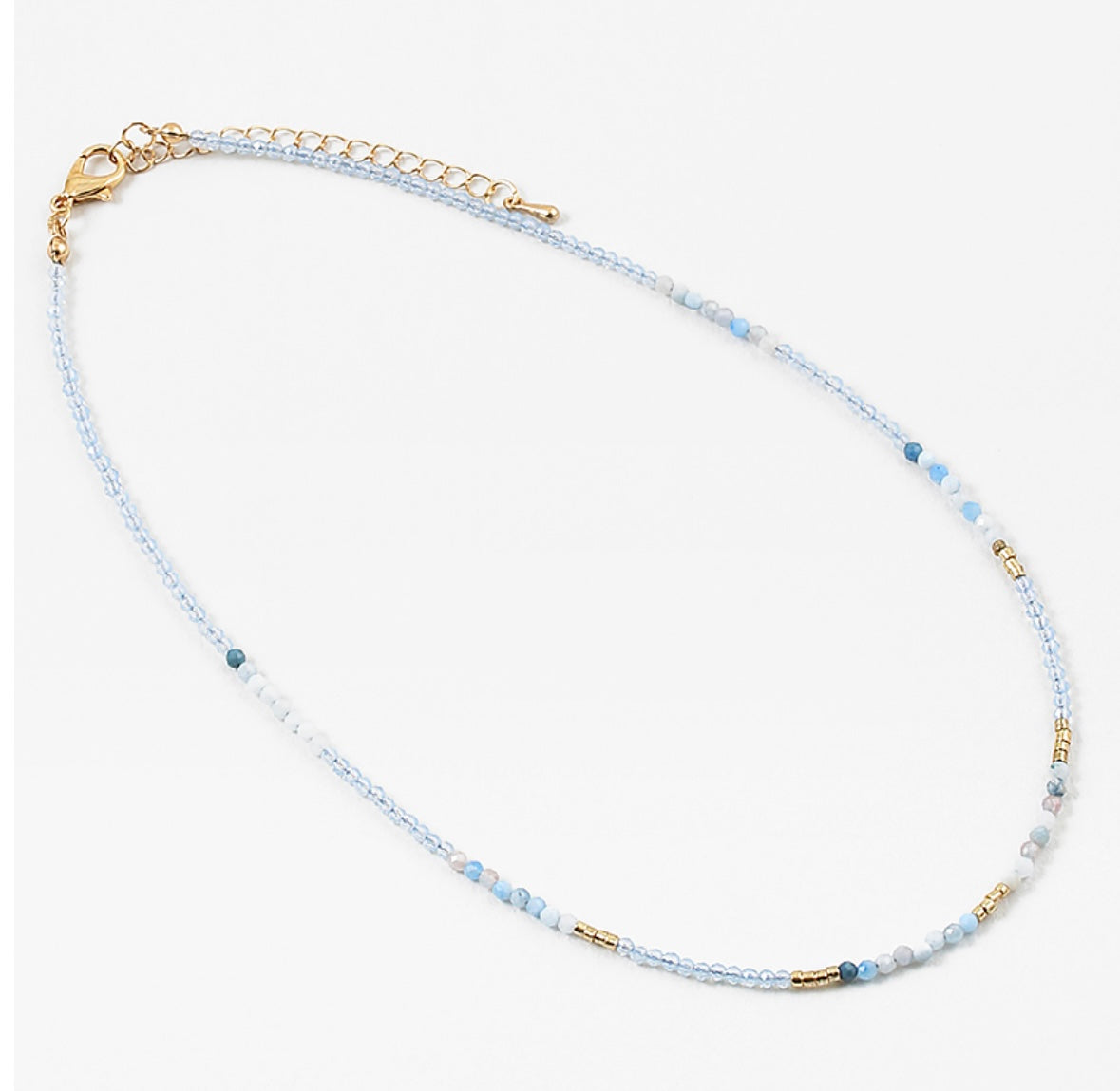 Dainty bead necklace with clear blue beads, gold and some solid blue beads.