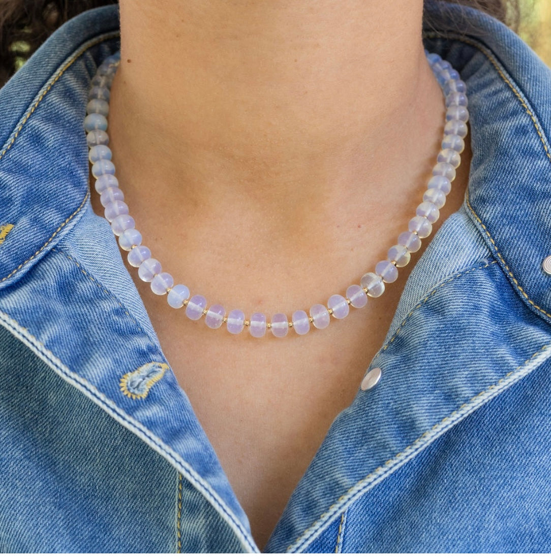 Person wearing a clear beaded necklace with a denim jacket