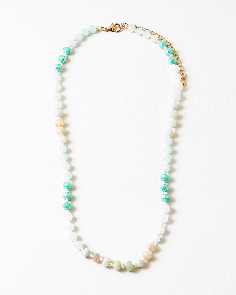 Necklace with beads in white, teal and beige on a white background