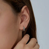 Close-up of an ear wearing a small hoop earring with a blurred background